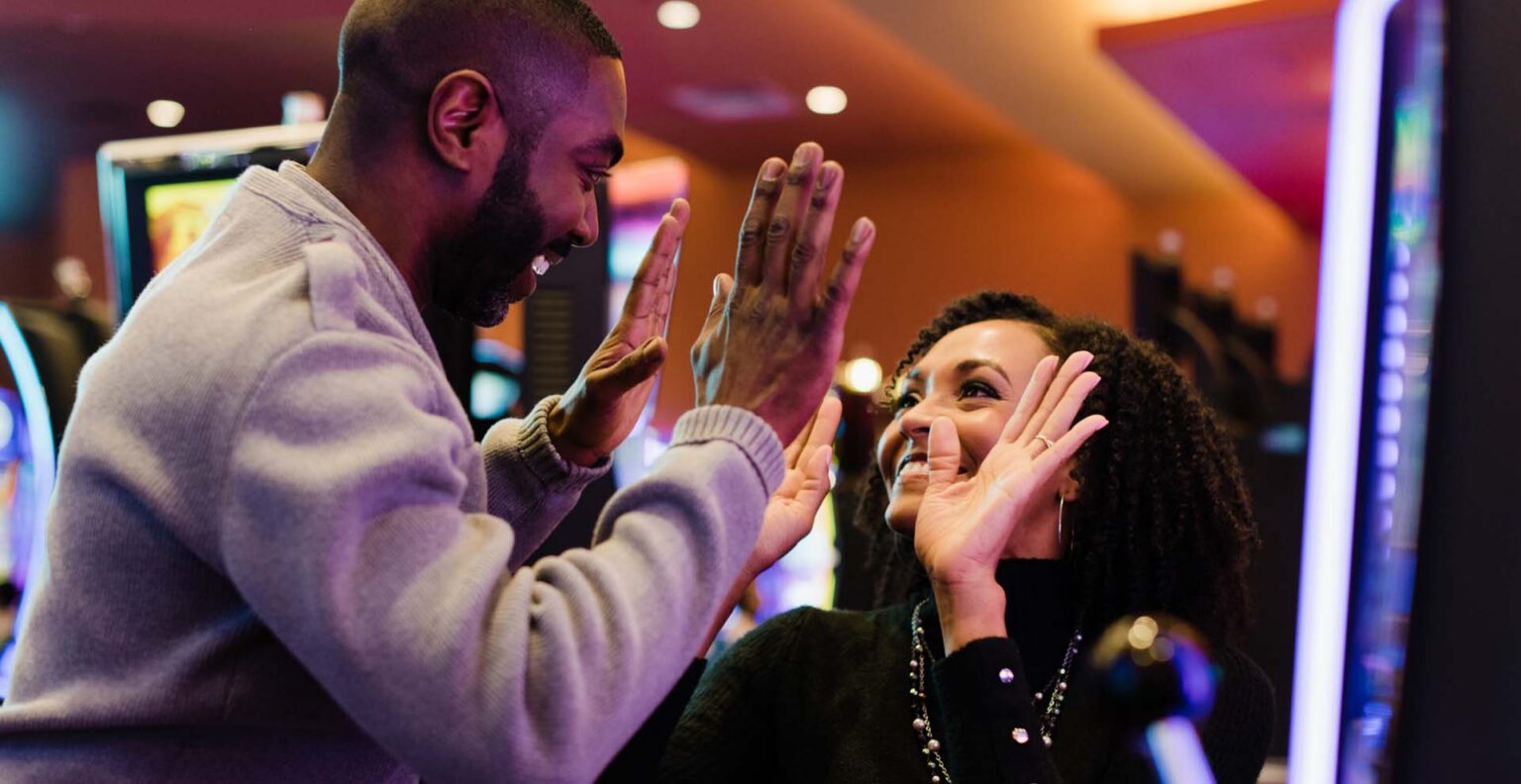 A man and a woman high fiving eachother in a casino.