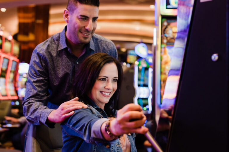 A man with his hand on a womens shoulder while playing a casino game and smiling