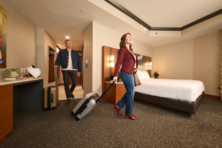 Couple happily walking into a hotel room with their suitcases
